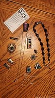 Overview photo of all silver jewelry pieces laid out on table, showing variety of rings, pendants, earrings and necklace with sterling silver tags visible.