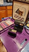 Overview of the Polaroid One Step camera, Vivitar flash, and craft kit on purple case