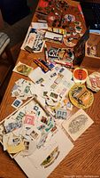 Overhead view of assorted metal pins, cloth patches and postage stamps spread on wooden table