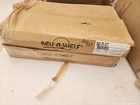 Closed cardboard box labeled Rev-A-Shelf with product code, showing original packaging and wear.