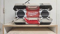 Front photo of Milwaukee jobsite radio on a white shelf, showing the red and black radio with two large front speakers and handle
