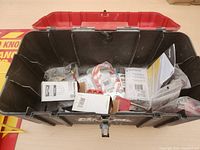 Open black and red toolbox showing various lock out safety tools, locks, tags, and manuals inside.