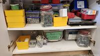 Photo of cabinet shelves containing multiple containers filled with screws and fasteners.