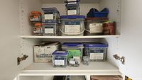 Photo showing inside of cabinet with multiple plastic containers of screws and fasteners, some labeled, arranged on two shelves.