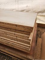 Stack of 3/4 inch thick white laminated particle board sheets and 5/8 inch light grey laminated sheets showing thickness and particle board cores.