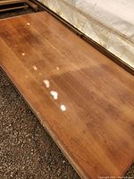 Full top view of a single large wood sheet showing wood grain and surface scratches.