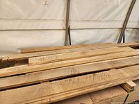 Multiple rough-sawn white oak boards stacked on plywood under a canopy