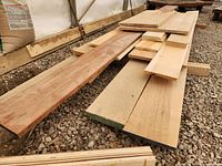 Multiple views of stacked solid wood lumber planks and boards outdoors on gravel floor.