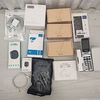 Overview of lot including 4 wireless chargers, box for battery case, cell phone, charging cables, USB charger and J33 audio receiver.