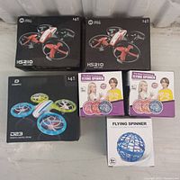 Photo of all items in lot showing the boxed mini drones and flying spinners arranged together.