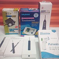 Image showing boxed PrimaCare blood pressure monitor, Life Source blood pressure monitor, Bonnie oral irrigator, and three boxes of ear wax removers with camera.