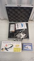 Two magnifying glasses inside a foam-padded protective carrying case along with instruction manuals and accessories. One magnifier is a new LED rechargeable spectacle magnifier in original box, and the other is a metal handheld magnifier.
