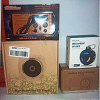 Overview of all boxed items: emergency alert solar crank radio, wall mountable CD player, waterproof speaker, vintage radio speaker
