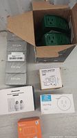 Overview of all smart plugs and adapters in original packaging including green timers, Amazon Smart Plug, travel adapter, and Simcoe plug