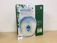 Photo of the boxed Pedagonic Foot Spa Massager with bonus Tea Tree Oil Foot Salt showing the product behind clear plastic and promotional text on the box front.