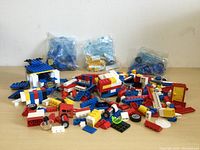Lego pieces scattered with some in small clear plastic bags, showing colorful assorted bricks and parts.