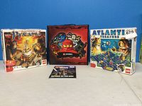 Photo of LEGO Pharaoh's Pyramid set, Ninjago box, Atlantis Treasure set, and Ninjago carrying case arranged on a white surface.