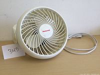Front view of white Honeywell fan with protective grille and attached power cord