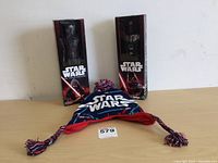Star Wars action figures Darth Vader and Kylo Ren in original boxed packaging alongside child's winter hat with Star Wars text and pompom.