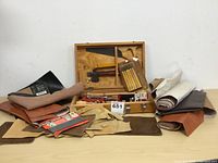 Full view of woodworking tools in open wooden case with leather pieces around