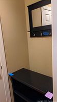 Bookshelf shown from above with blue tape on corner, placed in corner of room