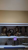 Photo of shelf displaying the mantel clocks, decorative light fixture, and candlesticks arranged together.