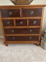 Front view of the wooden dresser showing the seven drawers, metal pulls, and legs.