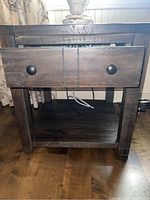 Front view of wood end table showing two drawers with black knobs and bottom shelf