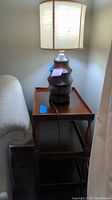 Side table with lamp on top next to a couch, showing the table's top surface and lamp in use position.