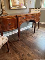 Front view showing central drawer, two curved side doors, legs