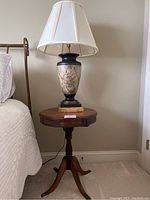 Full view of round wood end table with lamp on top, showing overall dimensions and style.