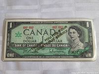 Front view of 1967 Canada Centennial Special Edition One Dollar Bank Note sealed in clear plastic, featuring Queen Elizabeth II and commemorative markings.