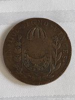 Obverse of the antique coin showing an ornate crest beneath a dome-like structure with floral elements and Latin inscription "IN HOC SIGNO VINCES"