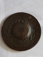 Front side of the coin showing emblem with wreath or laurel decoration.