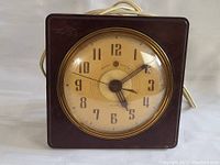 Front view of the antique General Electric Bakelite alarm clock showing clock face, hands, and casing with power cord.