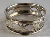 Close-up of silver napkin ring showing ornate pierced floral and geometric pattern on the body of the ring.