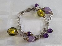 Sterling silver bracelet with large yellow-green glass beads and various amethyst beads attached to silver chain.