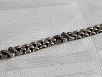 Close-up of the sterling silver bracelet showing pattern of small links with three larger decorative textured links spaced along the chain.