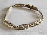 Full view of vintage sterling silver bracelet with lion cat cut out panels on white cloth background.