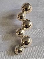 Front angle view showing the five silver spheres forming the vertical pendant.