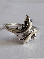 Close-up of a sterling silver ring with a leaf design, highlighting polished finish and decorative details.