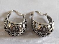 Front view of both sterling silver earrings showing detailed floral and scroll design with hinge clasp