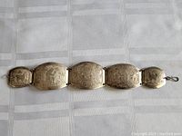 Full view of the vintage metal bracelet showing all five large linked panels and two smaller end panels with etched tribal motifs.
