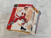 Stack of vintage hockey cards with a prominent Gordie Howe card on top, showing the player skating in red Detroit Red Wings uniform.
