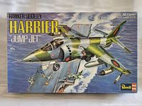 Front of the box showing the painted Harrier jet model soaring above an aircraft carrier with the title and brand Revell.