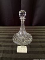 Front view of the clear glass decanter with stopper on top, showing diamond cut pattern and overall shape.
