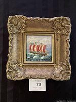 Full view of the small oil painting of a sailing ship on rough seas within a decorative gold frame showing the overall artwork and frame condition.