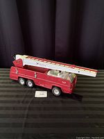 Photo of red metal Tonka firetruck with ladder fully extended showing side profile and condition