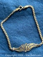 Photo showing entire gold bracelet laid out on blue fabric to highlight detail and overall condition.