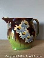 Front view of antique Royal Winton ceramic pitcher hand-painted with daisies and green to brown gradient background.